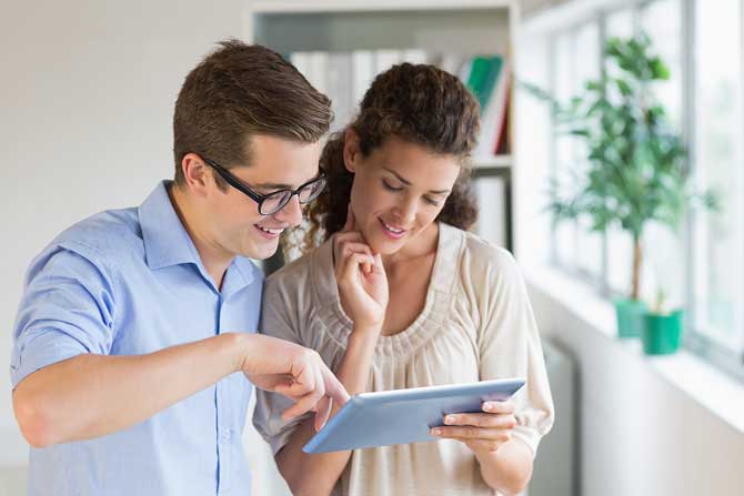 two agency owners using a tablet to hire young insurance agents